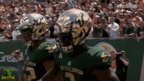 Two South Florida Football Players Are Walking On The Field During A Game GIF