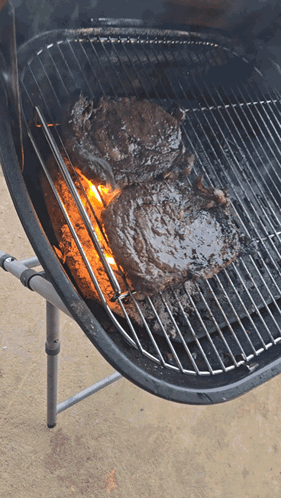 Two Steaks Cooking on Grill With Flames