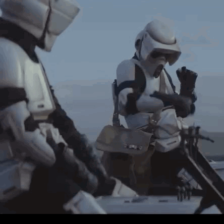 Two Storm Trooper Soldiers Are Standing Next To Each Other In The Desert . GIF
