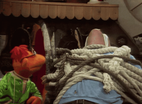 Two Stuffed Animals Are Tied Up With Ropes And One Is Wearing A Green Shirt GIF