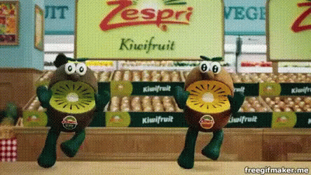 Two Stuffed Kiwi Fruits Are Dancing In Front Of A Zespri Sign GIF