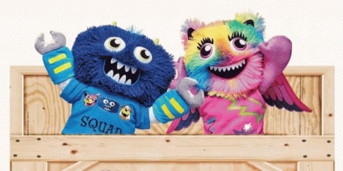 two stuffed monsters are sitting in a wooden box and one has a shirt that says squad