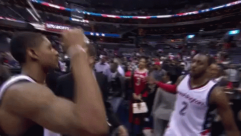 Two Washington Wizards Basketball Players Are Shaking Hands In A Stadium GIF