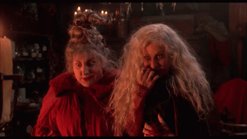 Two Witches Are Standing Next To Each Other And The Word Sorry Is On The Screen Behind Them GIF