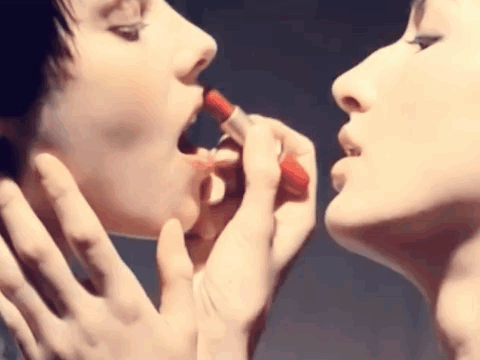 Two Women Applying Red Lipstick to Each Other