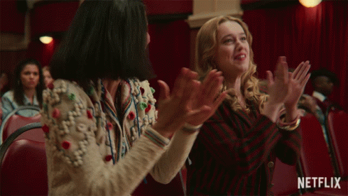Two Women Are Clapping In A Theater With A Netflix Logo In The Corner GIF