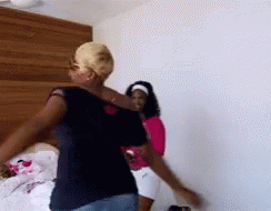 Two Women Are Dancing In A Room With A Wooden Headboard In The Background . GIF