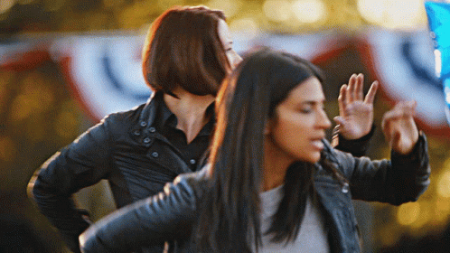 Two Women Are Dancing In Front Of A Banner That Says ' U.s. ' GIF