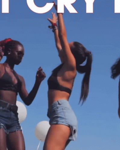 Two Women Are Dancing In Front Of A Blue Sky With The Word Cry In White GIF