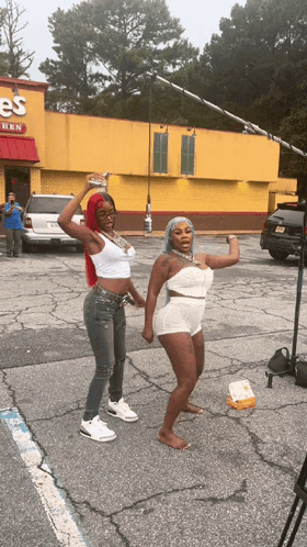 Two Women Are Dancing In Front Of A Chicken Restaurant GIF