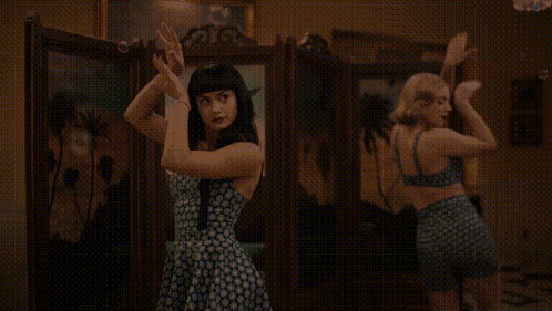 two women are dancing in front of a mirror in a room .