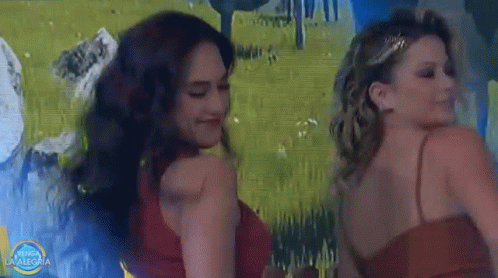 two women are dancing in front of a painting that says vamos la alegria