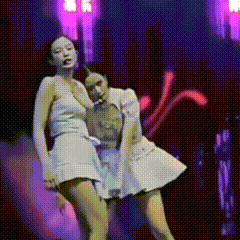 Two Women Are Dancing On A Stage In Front Of A Purple Background . GIF