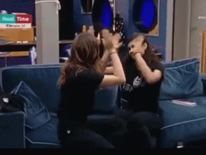 Two Women Are Fighting On A Couch With A Pizza Box In The Background That Says ' Roast Time ' GIF