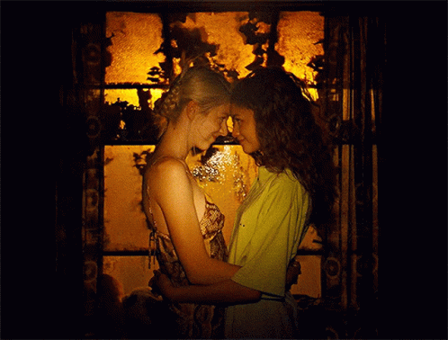 Two Women Are Hugging And Looking At Each Other In A Dark Room GIF