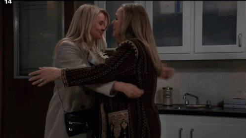Two Women Are Hugging In A Kitchen With The Number 14 In The Corner GIF