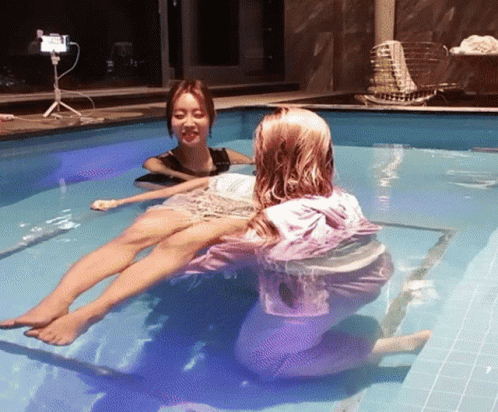 Two Women Are In A Swimming Pool And One Of Them Is Wearing A Pink Hoodie GIF