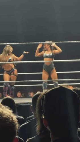 two women are in a wrestling ring with their arms in the air