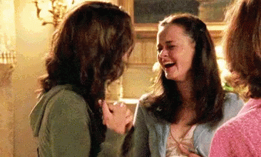 Two Women Are Laughing Together In A Living Room While Holding Hands . GIF