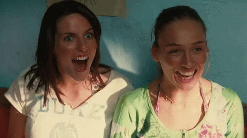 Two Women Are Laughing With One Wearing A Shirt That Says Duke On It GIF