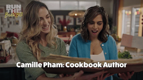 Two Women Are Looking At A Cookbook Titled Camille Pham GIF