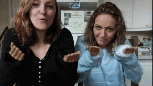 Two Women Are Making Funny Faces In Front Of A Refrigerator That Has A Sticker On It That Says " I Love You " GIF