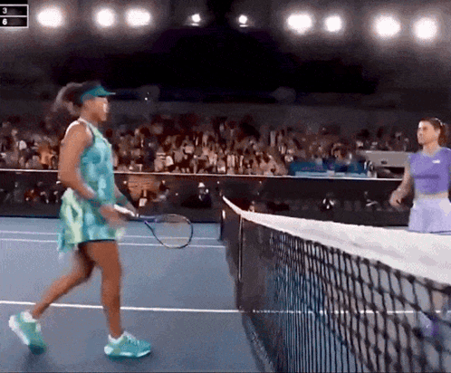 Two Women Are Playing Tennis On A Court And One Is Wearing A Blue Dress GIF
