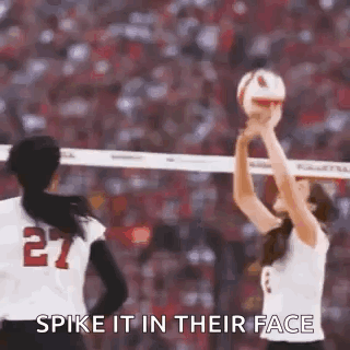 Two Women Are Playing Volleyball On A Court And One Of Them Is Holding A Volleyball In Her Hand . GIF