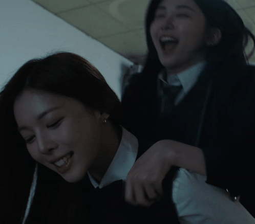 Two Women Are Playing With Each Other In A Dark Room And One Is Smiling GIF