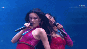 Two Women Are Singing Into Microphones On A Stage With Samsung In The Background GIF
