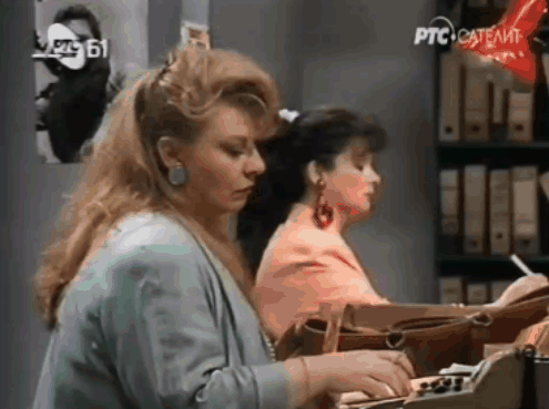 Two Women Are Sitting At A Desk With Ptc Satellite Written On The Bottom GIF