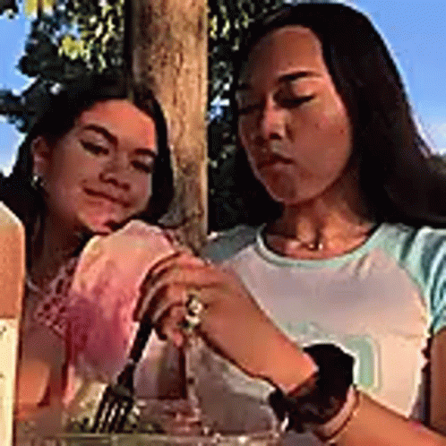 Two Women Are Sitting At A Table Eating Food . GIF