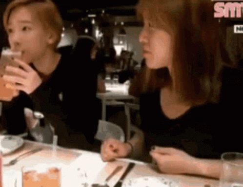 Two Women Are Sitting At A Table In A Restaurant Drinking Beer And Eating Food . GIF