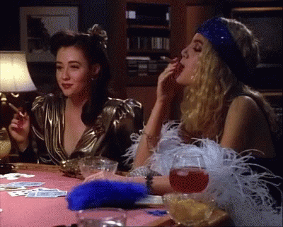 Two Women Are Sitting At A Table Smoking Cigarettes GIF
