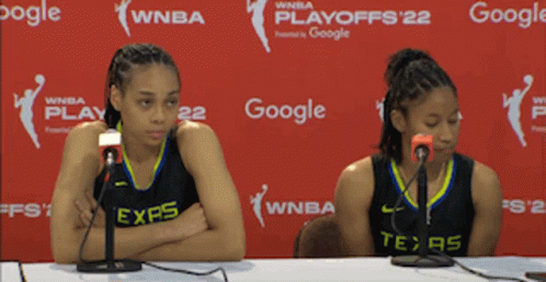 Two Women Are Sitting At A Table With Microphones In Front Of A Google Banner GIF