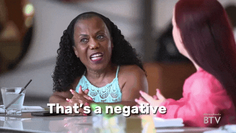 Two Women Are Sitting At A Table With The Words That 'S A Negative Written On The Screen GIF