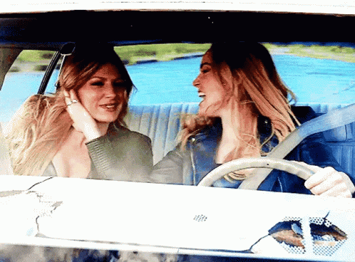 Two Women Are Sitting In A Car Laughing And Talking GIF