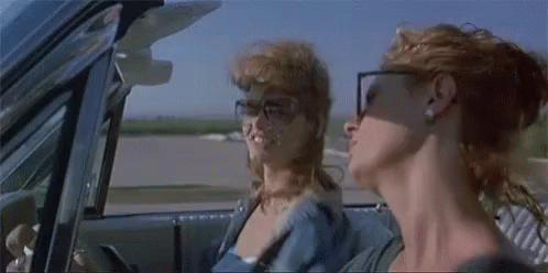 Two Women Are Sitting In A Car Looking Out The Window . GIF