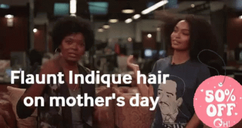 Two Women Are Sitting In Front Of A Sign That Says Flaunt Indicue Hair On Mother 'S Day GIF