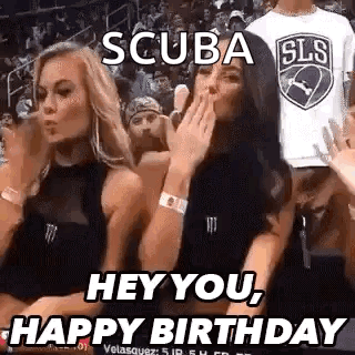 Two Women Are Sitting In The Stands At A Basketball Game And One Is Blowing A Kiss . GIF