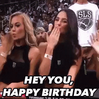Two Women Are Sitting In The Stands At A Basketball Game And One Is Blowing A Kiss . GIF