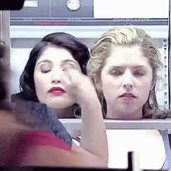 Two Women Are Sitting Next To Each Other And One Is Covering Her Eyes With Her Hand GIF