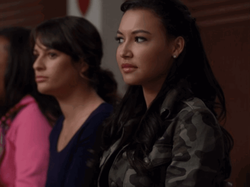 Two Women Are Sitting Next To Each Other And One Is Wearing A Camo Jacket GIF