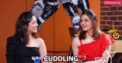 Two Women Are Sitting Next To Each Other And The Word Cuddling Is On The Bottom GIF