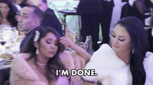 Two Women Are Sitting Next To Each Other At A Table And One Of Them Is Holding Another Woman 'S Arm . GIF