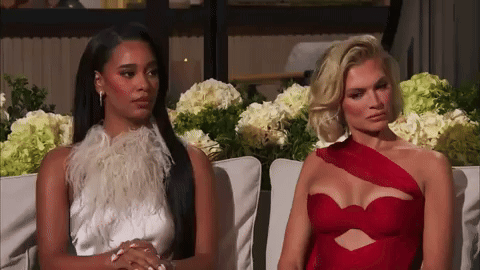 Two Women Are Sitting Next To Each Other On A Couch And One Is Wearing A Red Dress GIF