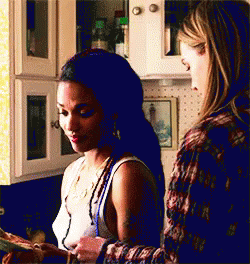 Two Women Are Standing In A Kitchen Looking At A Piece Of Paper . GIF