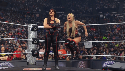 Two Women Are Standing In A Wrestling Ring With A W On The Ropes GIF