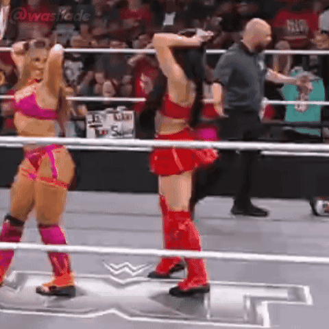 Two Women Are Standing In A Wrestling Ring With Their Arms Up . GIF