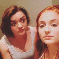 Two Women Are Standing Next To Each Other And Looking At Each Other . One Of The Women Is Wearing A White Tank Top . GIF